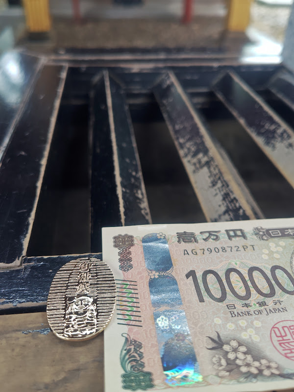 【大国神社のお賽銭箱の縁に御種銭を置いて参拝】
